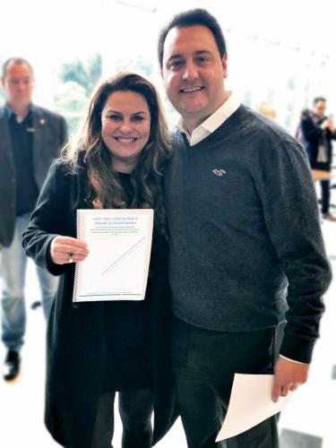 A superintendente-geral Keli Guimarães entregando o projeto "Visão 2053" ao governador Ratinho